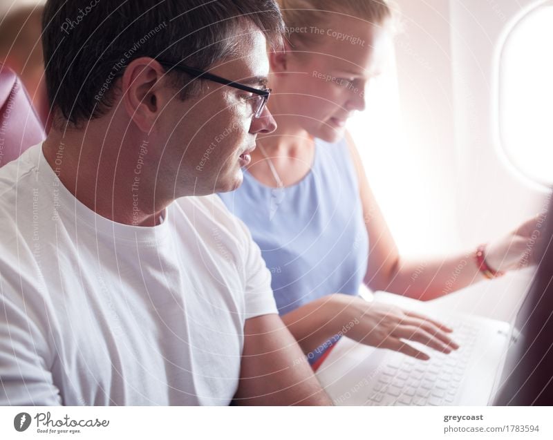 Man and woman are sitting by and watching something in laptop during the flight. Vacation & Travel Trip Business Computer Notebook Technology Young woman