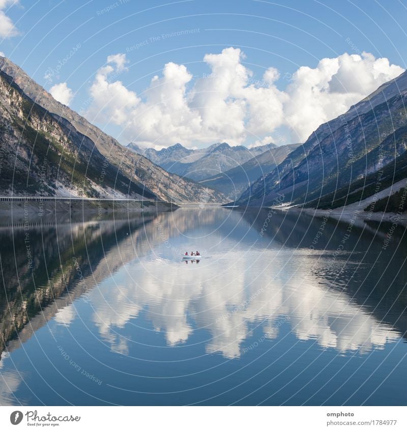 Lake in the high Alps with boat, cold water and reflections of a blue sky and clouds Beautiful Vacation & Travel Tourism Summer Mountain Hiking Nature Landscape