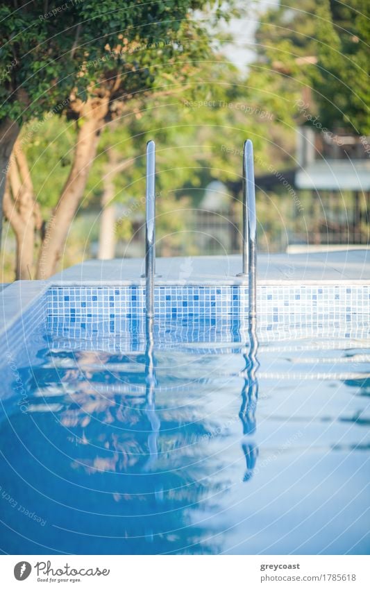 View to the outdoor pool with stairs and clear blue water. Green trees in background. Recreation on resort Luxury Relaxation Spa Swimming pool