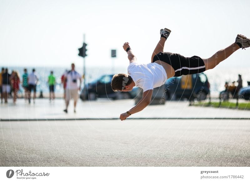 Young sportive man performing acrobatics in city square. Motion shot during tumbleset in the air Lifestyle Summer Sports Human being Man Adults Town Street