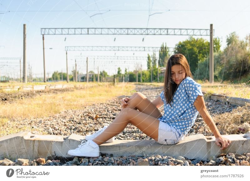 Brunette girl teenager sitting on the concrete of unfinished rail track outside the city Summer Girl Youth (Young adults) 1 Human being 13 - 18 years Landscape