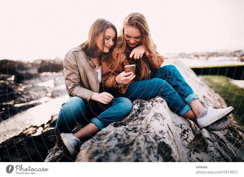 Happy Young teenager girls looking at smart phone Lifestyle Joy Freedom Beach Ocean Cellphone PDA Technology Entertainment electronics Internet Human being Girl