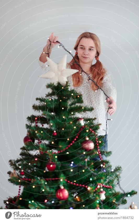 Young girl decorating Christmas tree with lights at home Lifestyle Joy Decoration Feasts & Celebrations Christmas & Advent Human being Child Girl 1 8 - 13 years