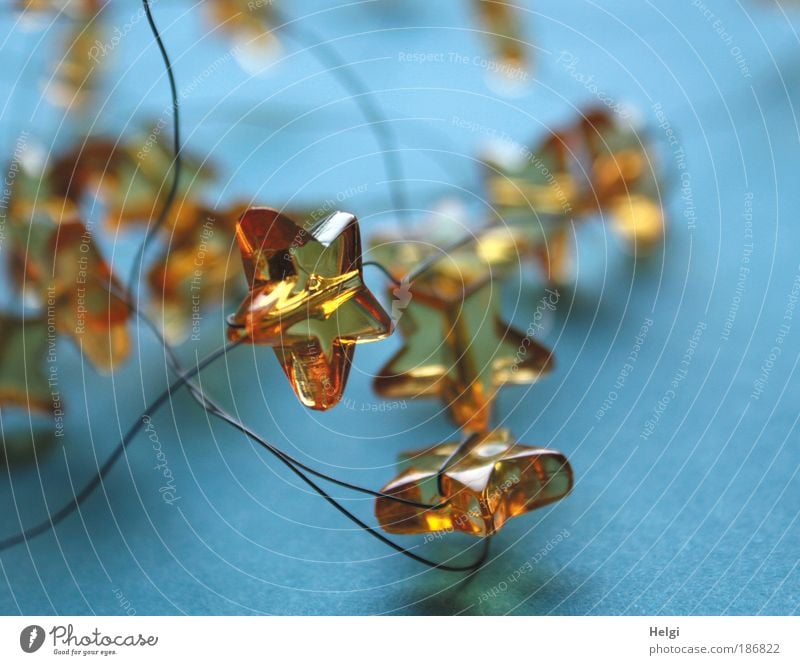 Close-up of yellow glass stars with wire in front of a blue background Decoration Kitsch Odds and ends Glass Metal Sign Star (Symbol) Glittering Esthetic