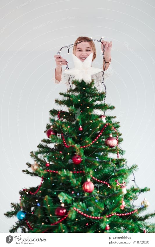 Young girl decorating Christmas tree with lights at home Lifestyle Joy Decoration Feasts & Celebrations Christmas & Advent Human being Girl Youth (Young adults)