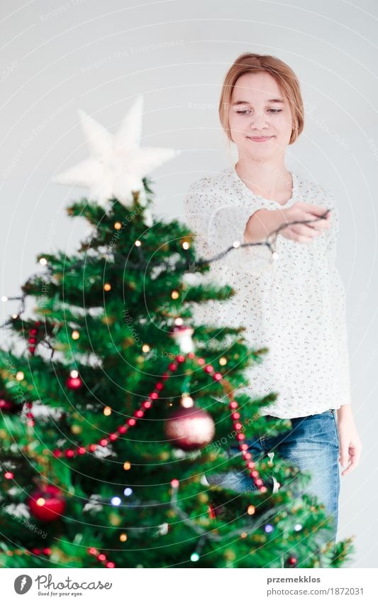 Young girl decorating Christmas tree with lights at home Lifestyle Joy Decoration Feasts & Celebrations Christmas & Advent Human being Girl Youth (Young adults)