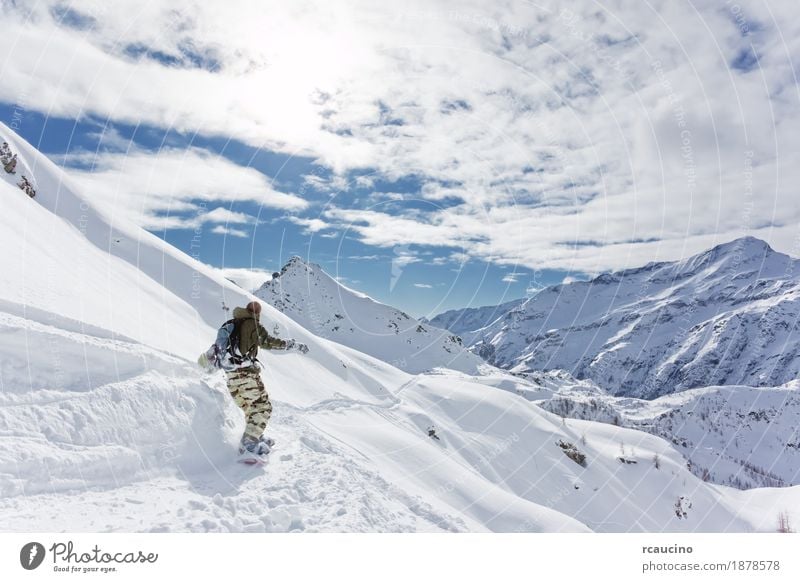 Snowboarder goes downhill over a snowy mountain landscape Vacation & Travel Tourism Winter Mountain Sports Skiing Ski run Boy (child) 1 Human being Landscape