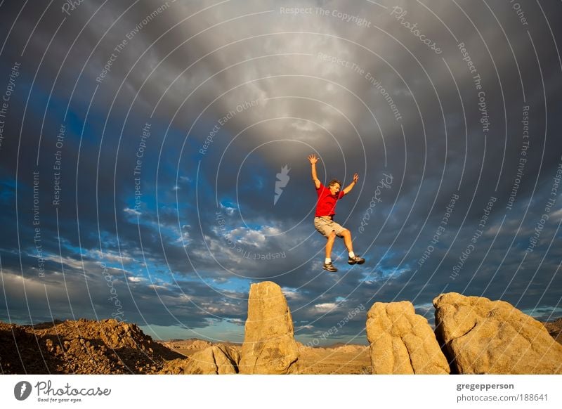 Rock climber on the summit. Adventure Freedom Hiking Climbing Mountaineering Man Adults 1 Human being Storm clouds Peak Hiking boots Flying Jump Tall Bravery