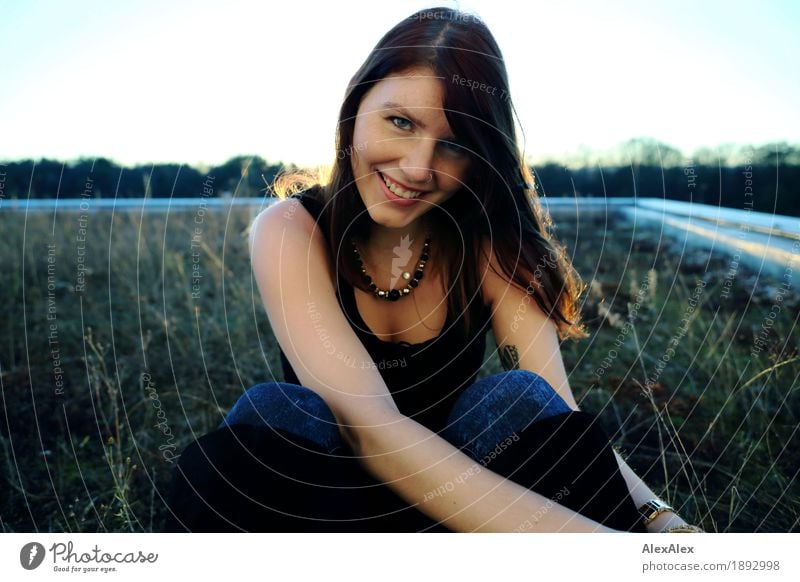 Young woman with freckles sits on a high flat roof in the evening light and smiles at the camera Lifestyle pretty Roof garden Youth (Young adults) Face