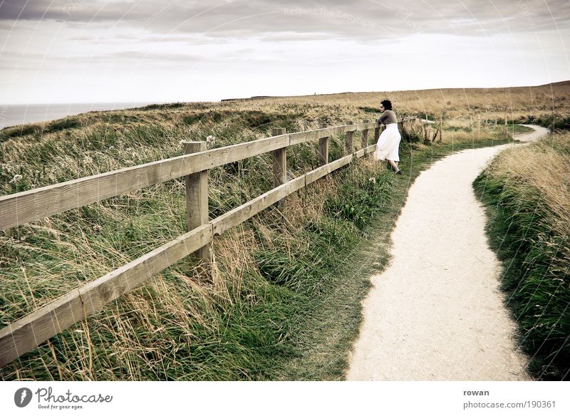 windy day at the sea Woman Adults Looking Lanes & trails Fence Vantage point Dress Lake Ocean Grass Warmth Summer Relaxation Break Hiking To go for a walk White