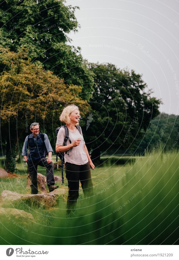 Happy senior couple on a hike trough green fields Lifestyle Joy Leisure and hobbies Tourism Adventure Hiking Human being Female senior Woman Male senior Man