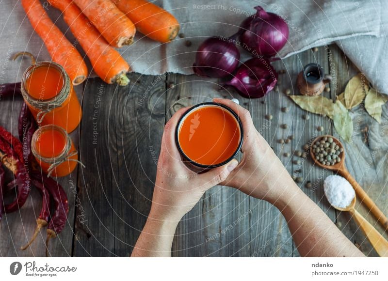 female hands holding an iron mug with carrot juice Food Vegetable Herbs and spices Drinking Juice Cup Mug Spoon Body Table Young woman Youth (Young adults) Arm