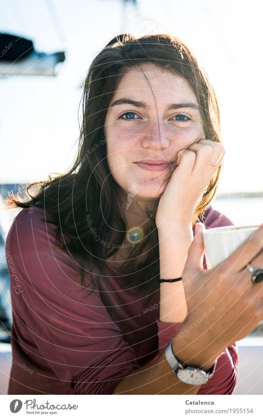 Young woman with coffee cup in hand looks at camera with smile Drinking Coffee Sailing Summer Ocean Yacht harbour Coffee cup Observe To enjoy Fragrance pretty