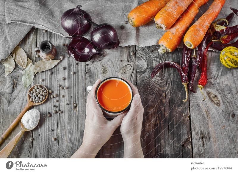 cup of carrot juice in female hands on a gray wooden surface Vegetable Herbs and spices Nutrition Drinking Cold drink Juice Cup Spoon Table Woman Adults Hand 1