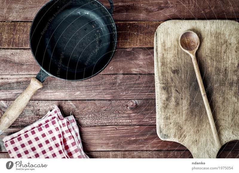 empty black metal pan and cutting board on a wooden surface Pan Spoon Design Table Kitchen Tool Cloth Wood Metal Above Clean Brown Black tableware Tablecloth