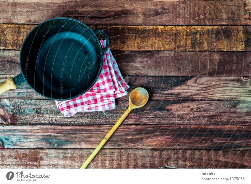 empty black metal pan with a wooden spoon Crockery Pan Spoon Design Table Kitchen Restaurant Cloth Wood Metal Above Clean Brown Black tableware Tablecloth