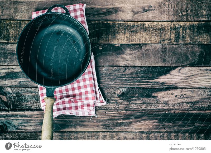 Empty frying pan on a textile napkin Crockery Pan Table Kitchen Restaurant Cloth Wood Metal Above Clean Brown Black tableware Tablecloth Vantage point iron