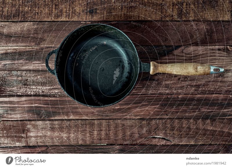 Black cast-iron frying pan on a brown wooden surface Crockery Pan Design Table Kitchen Restaurant Tool Wood Metal Above Clean Brown copy Vantage point Frying