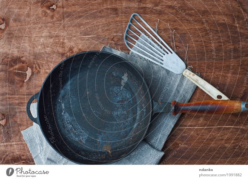 Cast iron black frying pan with kitchen iron shovel Crockery Pan Table Kitchen Restaurant Tool Cloth Wood Metal Above Clean Brown Black tableware Tablecloth