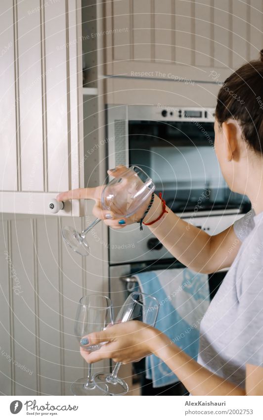 Anonymous woman putting glasses into cupboard in lovely kitchen. Lifestyle Living or residing Flat (apartment) House (Residential Structure) Kitchen Woman