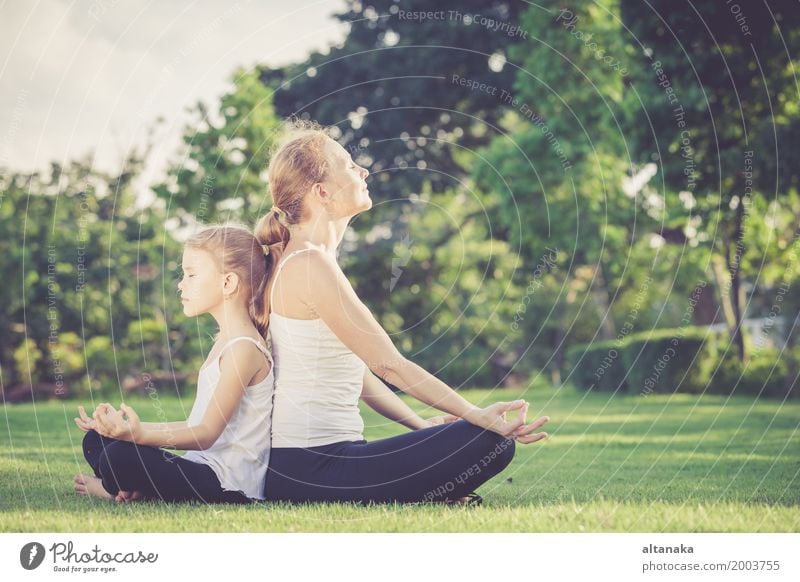 Mother and daughter doing yoga exercises on grass in the park at the day time Lifestyle Joy Happy Beautiful Body Wellness Harmonious Relaxation Meditation