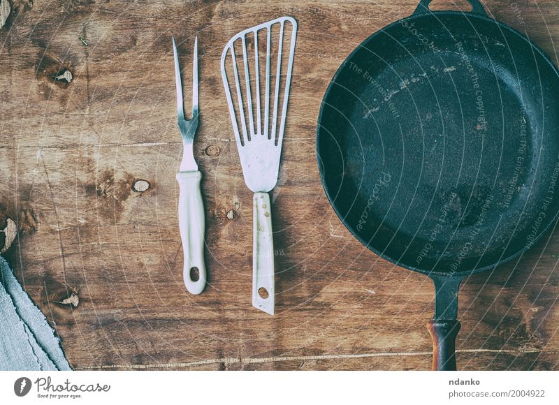 Empty black cast-iron frying pan with vintage kitchen items Crockery Pan Table Kitchen Restaurant Tool Wood Metal Above Clean Brown Black tableware spatula