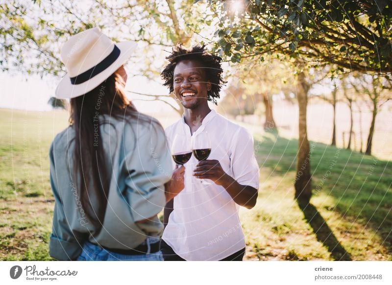 Mixed race couple having wine together on summer day Drinking Joy Summer Young woman Youth (Young adults) Young man Friendship Couple Partner Park Afro Smiling