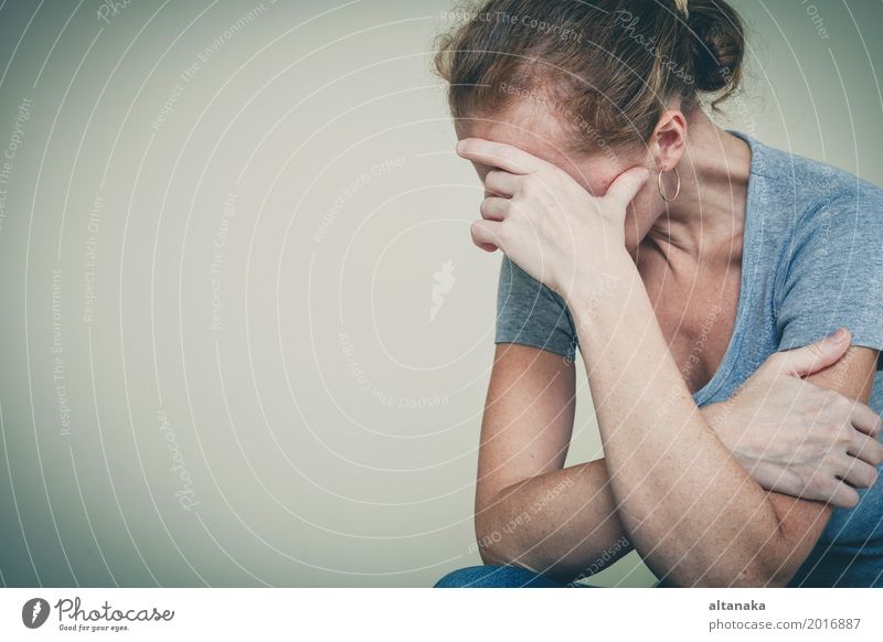 one sad woman sitting near a wall and holding her head in her hands Lifestyle Face Human being Girl Woman Adults Family & Relations Sadness Cry Emotions Concern