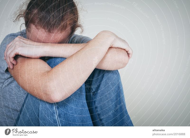 one sad woman sitting near a wall and holding her head in her hands Lifestyle Face Human being Girl Woman Adults Family & Relations Sadness Cry Emotions Concern