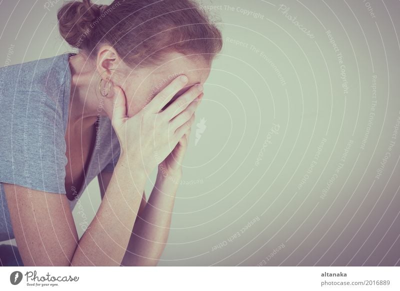 one sad woman sitting near a wall and holding her head in her hands Lifestyle Face Human being Girl Woman Adults Family & Relations Sadness Cry Emotions Concern