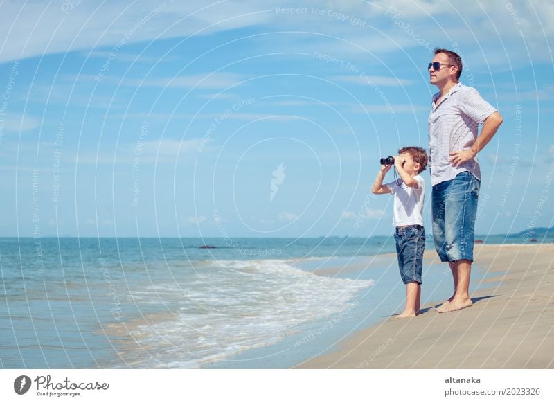 Father and son with binoculars standing on the beach at the day time. Concept of friendly family. Lifestyle Joy Relaxation Leisure and hobbies Playing