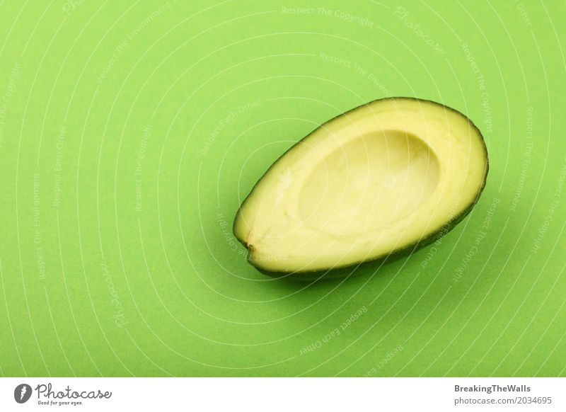 Fresh avocado half on green paper background Vegetable Nutrition Vegetarian diet Paper Natural Green Colour Half Top Vantage point Cut Slice Ingredients cooking