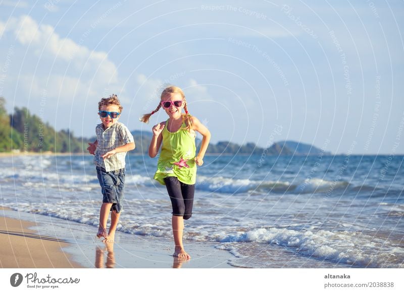 Happy children playing on the beach at the day time. Lifestyle Joy Relaxation Leisure and hobbies Playing Vacation & Travel Adventure Freedom Summer Sun Beach