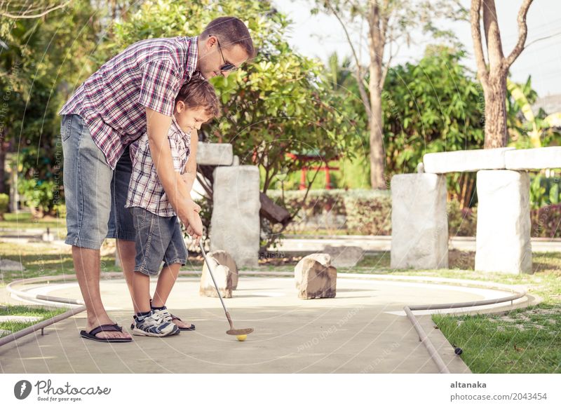 Cheerful young man teaching his son to play mini golf Lifestyle Joy Happy Relaxation Leisure and hobbies Playing Vacation & Travel Freedom Summer Sun Club Disco