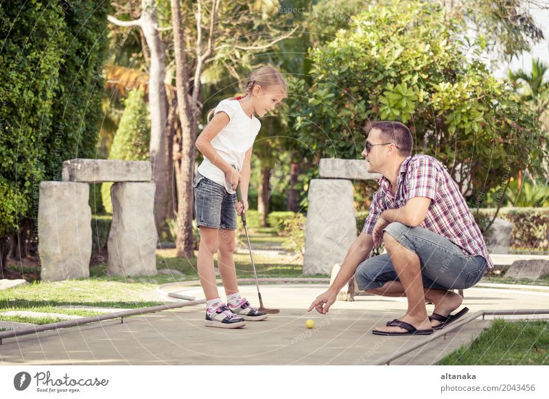 Cheerful young man teaching his daughter to play mini golf Lifestyle Joy Happy Relaxation Leisure and hobbies Playing Vacation & Travel Freedom Summer Sun Club