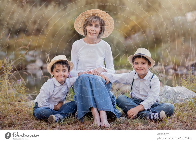 Grandmother with her grandchildren sitting in the field Lifestyle Human being Masculine Feminine Child Toddler Boy (child) Female senior Woman