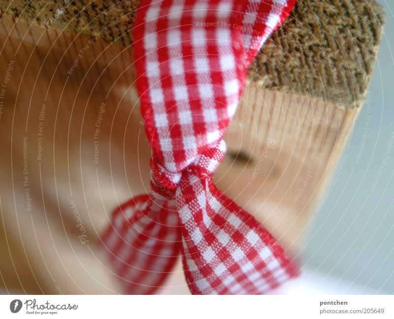 A bow made of red and white checked fabric attached to a wooden board. Gift ribbon. Christmas. Giving Gift wrapping Reddish white Cloth Bow Checkered Adornment