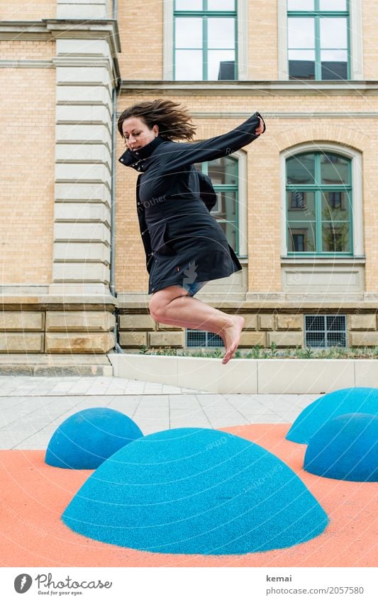 Woman in coat jumps barefoot on blue rubber hills Lifestyle Well-being Contentment Leisure and hobbies Playing Playground Vacation & Travel Freedom City trip