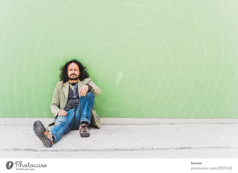 Man sitting on the floor in front of a green wall Lifestyle Style Relaxation Calm Leisure and hobbies City trip Human being Masculine Young man