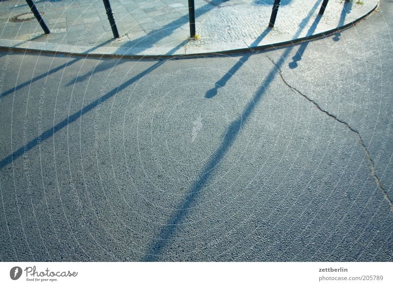 curve Street Road traffic Asphalt Sidewalk Curbside Bollard Border Handrail Sun Shadow Evening Curve Line Round Parking lot Copy Space Deserted