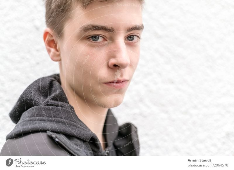 portrait of a smiling young man male boy teen teenager confident caucasian smile smirk standing wall white lucky jacket black lifestyle youth funny hoodie