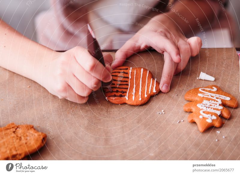 Girl decorating Christmas gingerbread cookies with chocolate Decoration Table Feasts & Celebrations Human being Hand 1 Make Tradition Baking biscuit cake