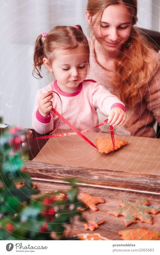 Girls tying baked Christmas gingerbread cookies with ribbon Lifestyle Decoration Feasts & Celebrations Child Craft (trade) Human being Family & Relations 2