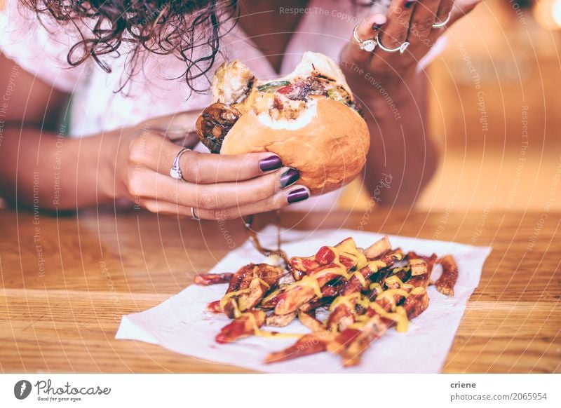 Close-up of woman eating fries and Hamburger Meat Bread Roll Herbs and spices Eating Diet Fast food Lifestyle Restaurant Woman Adults Afro Fat Delicious Joy