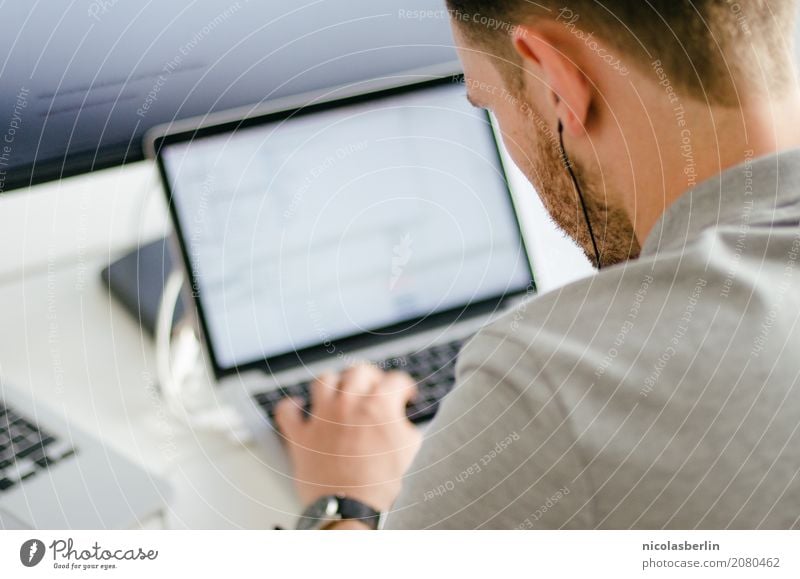 Young man works on a laptop in the start-up and listens to music through in-ear headphones Professional training Apprentice Internship Study