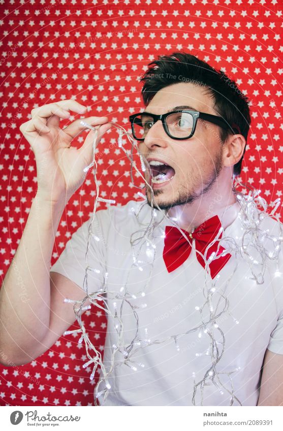 Funny portrait of a young man biting christmas lights Lifestyle Elegant Style Feasts & Celebrations Christmas & Advent New Year's Eve Human being Masculine