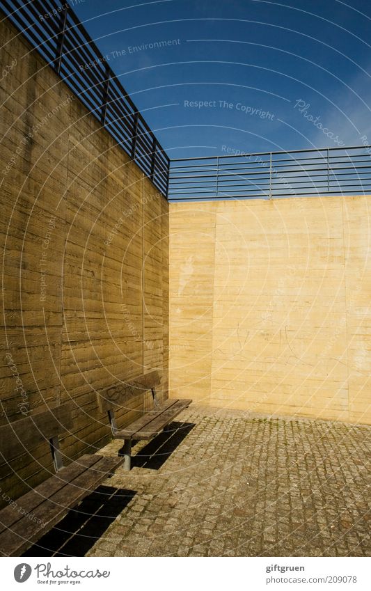 urban spaces Wall (barrier) Wall (building) Relaxation Esthetic Sharp-edged Simple Modern Sterile Yellow Bench Seating Handrail Sky Cobblestones Paving stone