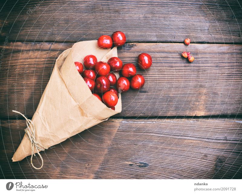 Ripe red cherry in a paper bag Fruit Dessert Vegetarian diet Paper Wood Diet Eating Fresh Retro Juicy Red background Berries Cherry food Harvest many Organic