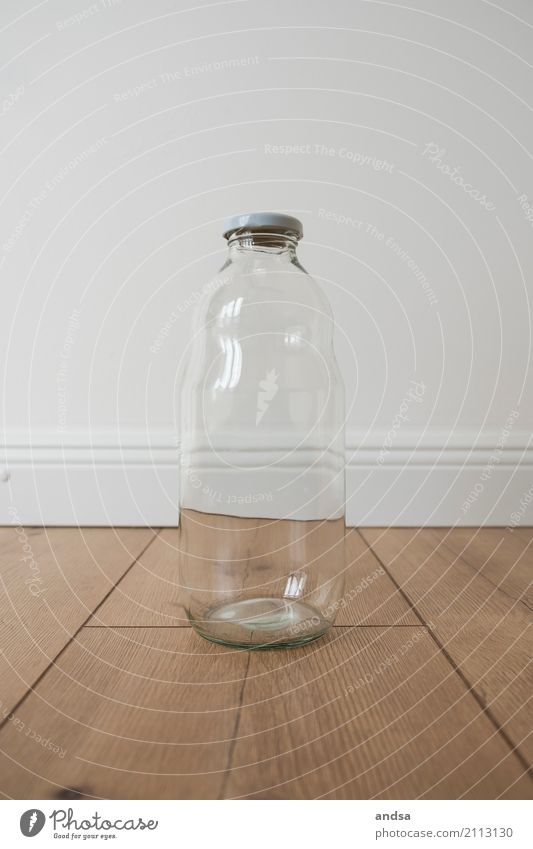 Empty milk bottle on a wooden floor in front of a white wall Milk bottle Glassbottle Bottle white background Baseboard Art Still Life White Interior shot