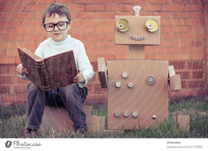 One little boy reading to robot from cardboard boxes outdoors. Concept of science and education. Lifestyle Joy Happy Beautiful Relaxation Leisure and hobbies